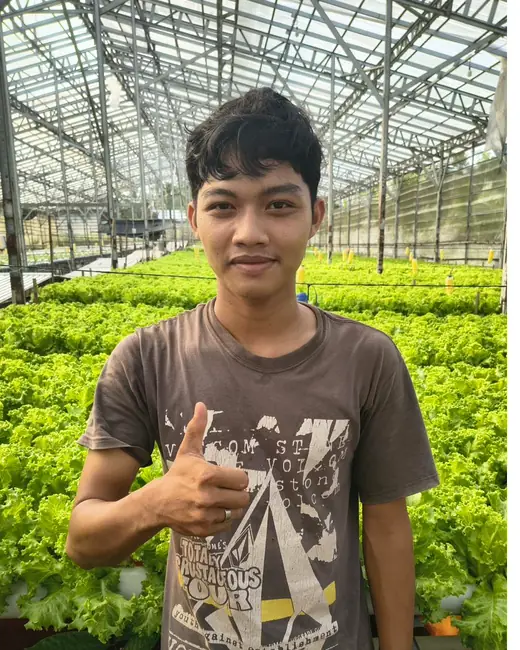 Anggota tim DD Farm mengacungkan jempol di depan instalasi selada